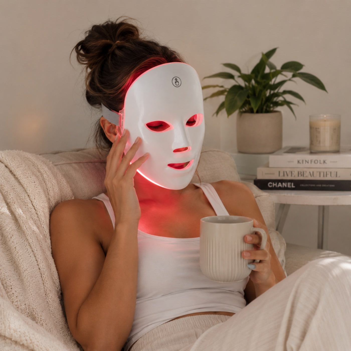 Mujer usando la máscara de terapia de luz LED relajada en casa